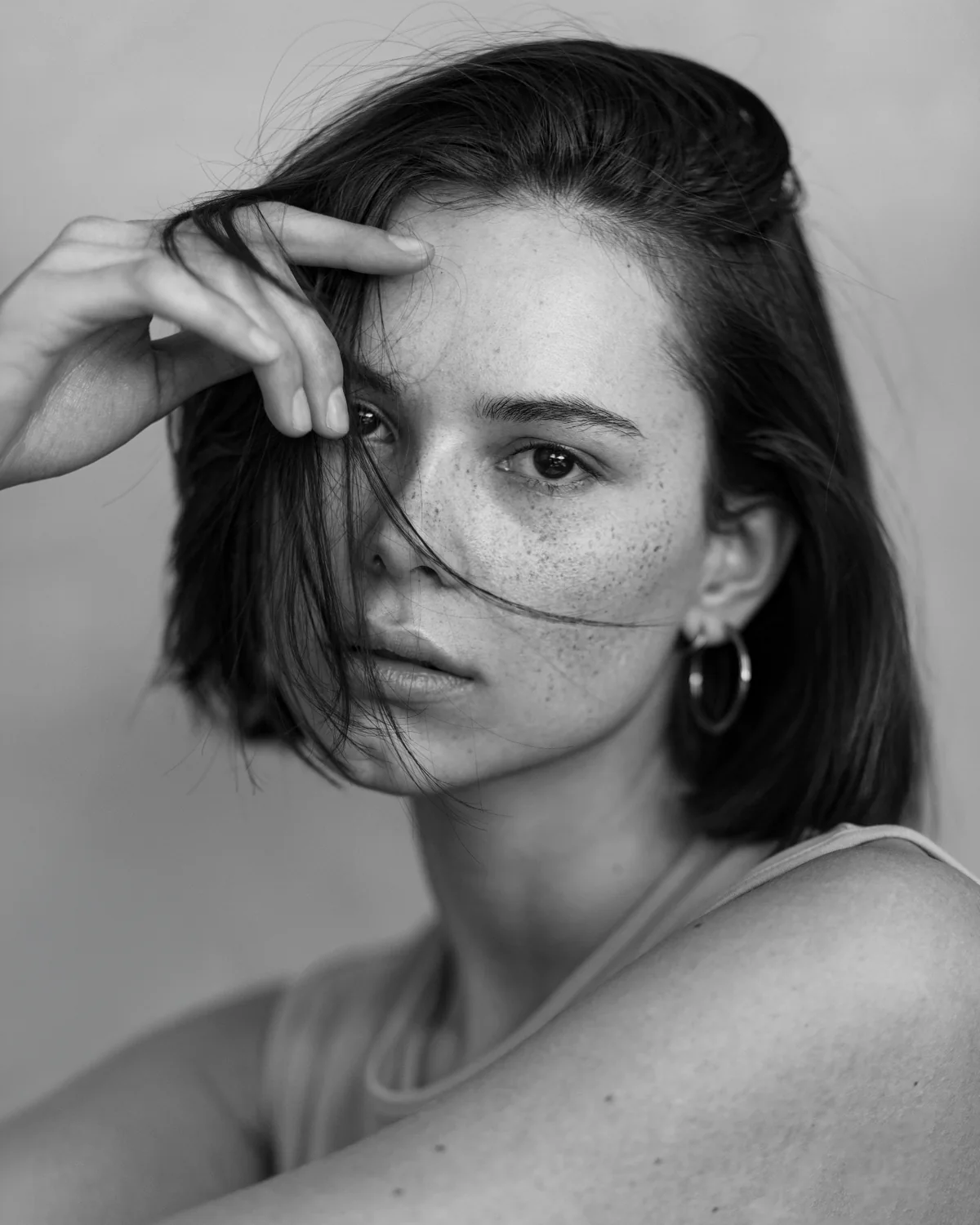 Zwart-wit close-upportret van model Aline met sproeten en hand bij het gezicht, gefotografeerd door Robin Wagenaar